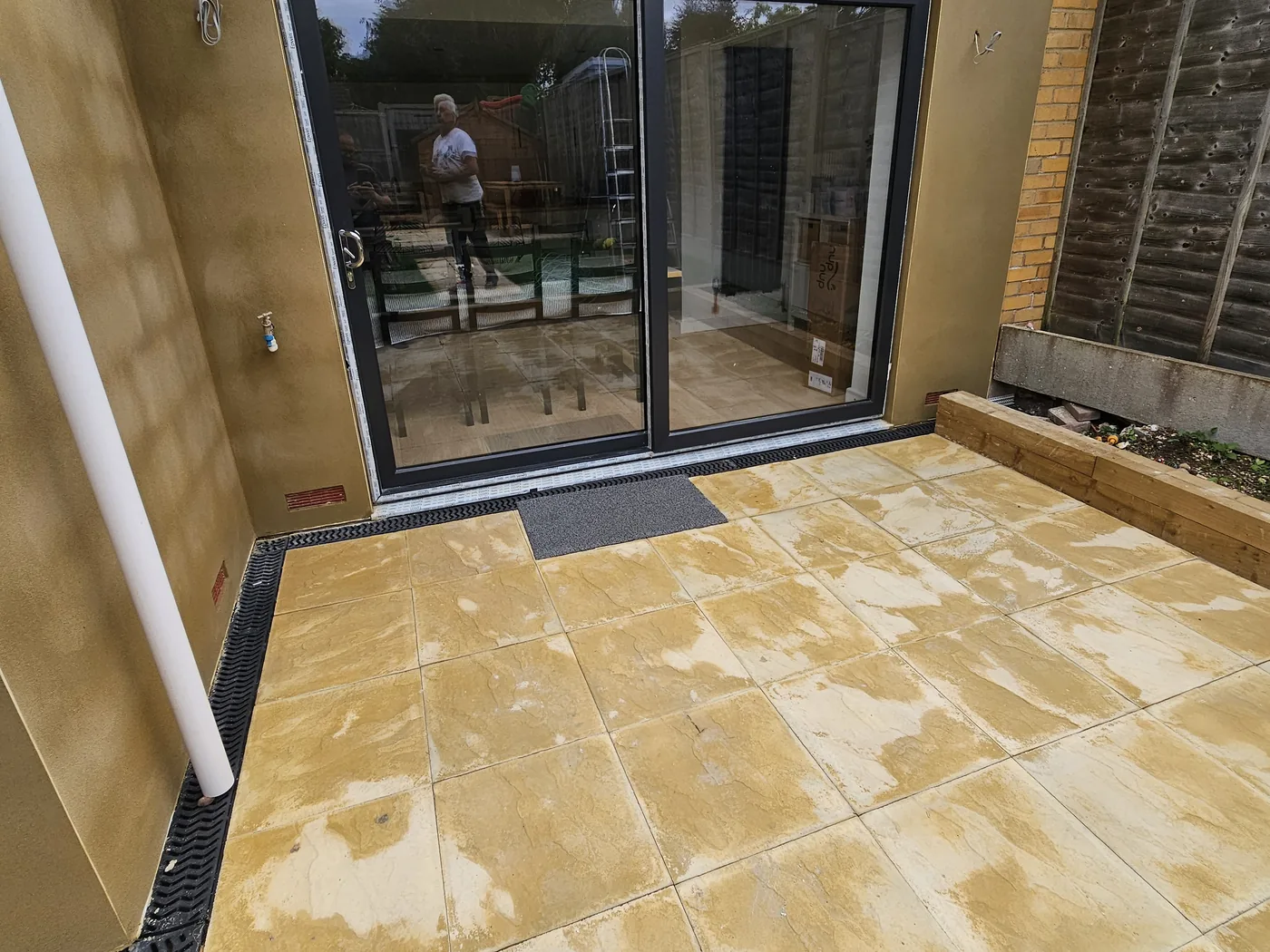 New extension finished in coloured render with sliding doors and a new sandstone patio