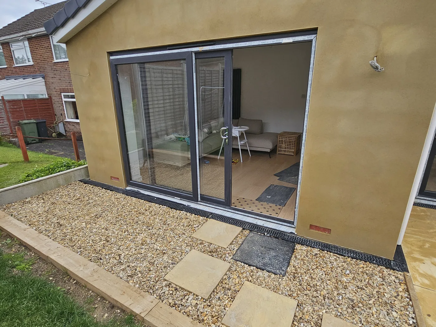 Rear extension rendered in ochre monocouche with new roof and gravel border