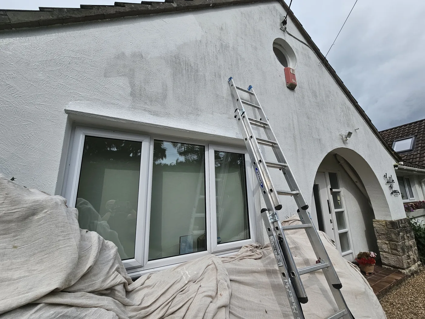 Exterior wall part painted, dust sheets down over the beds and ladder up