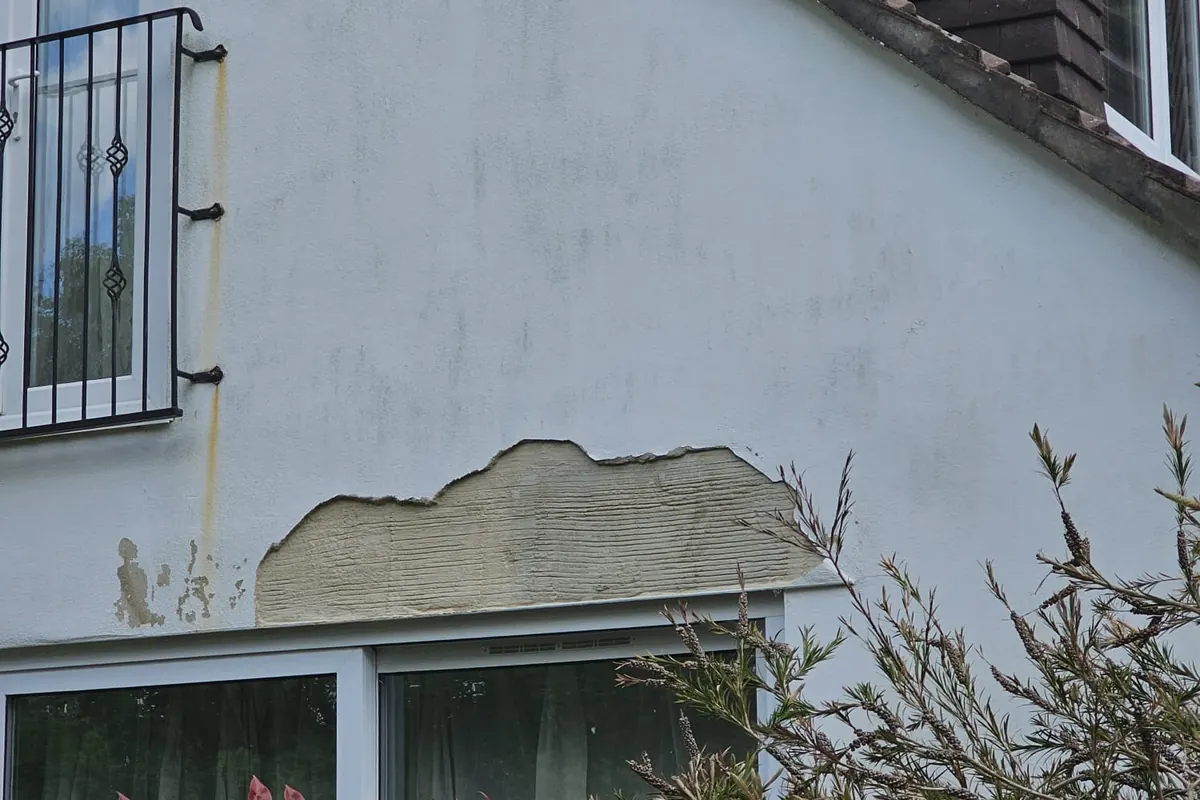 Blown external render on a gable wall, patched and failing